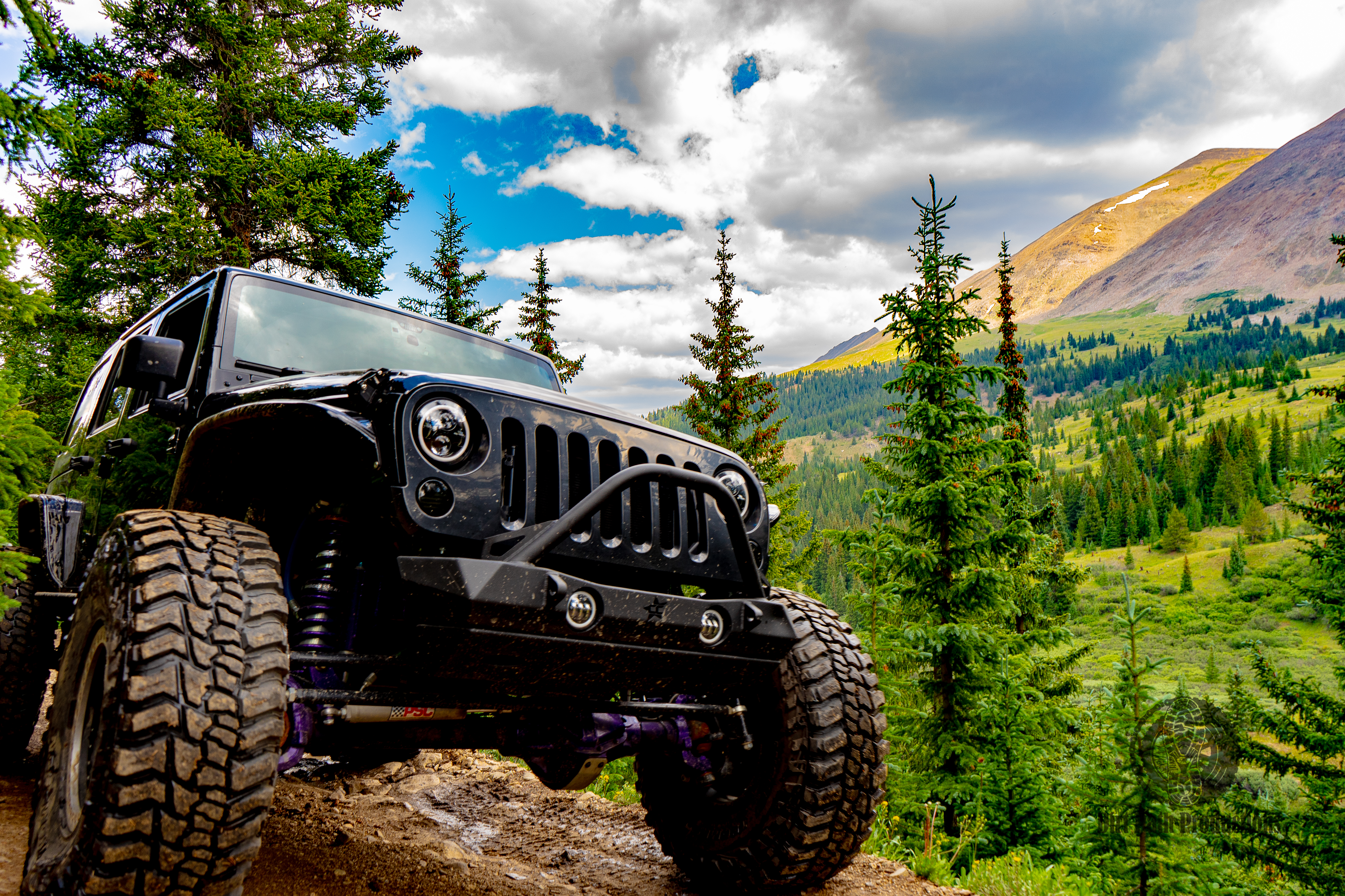 Black Jeep with mountain backdrop and dramatic clouds