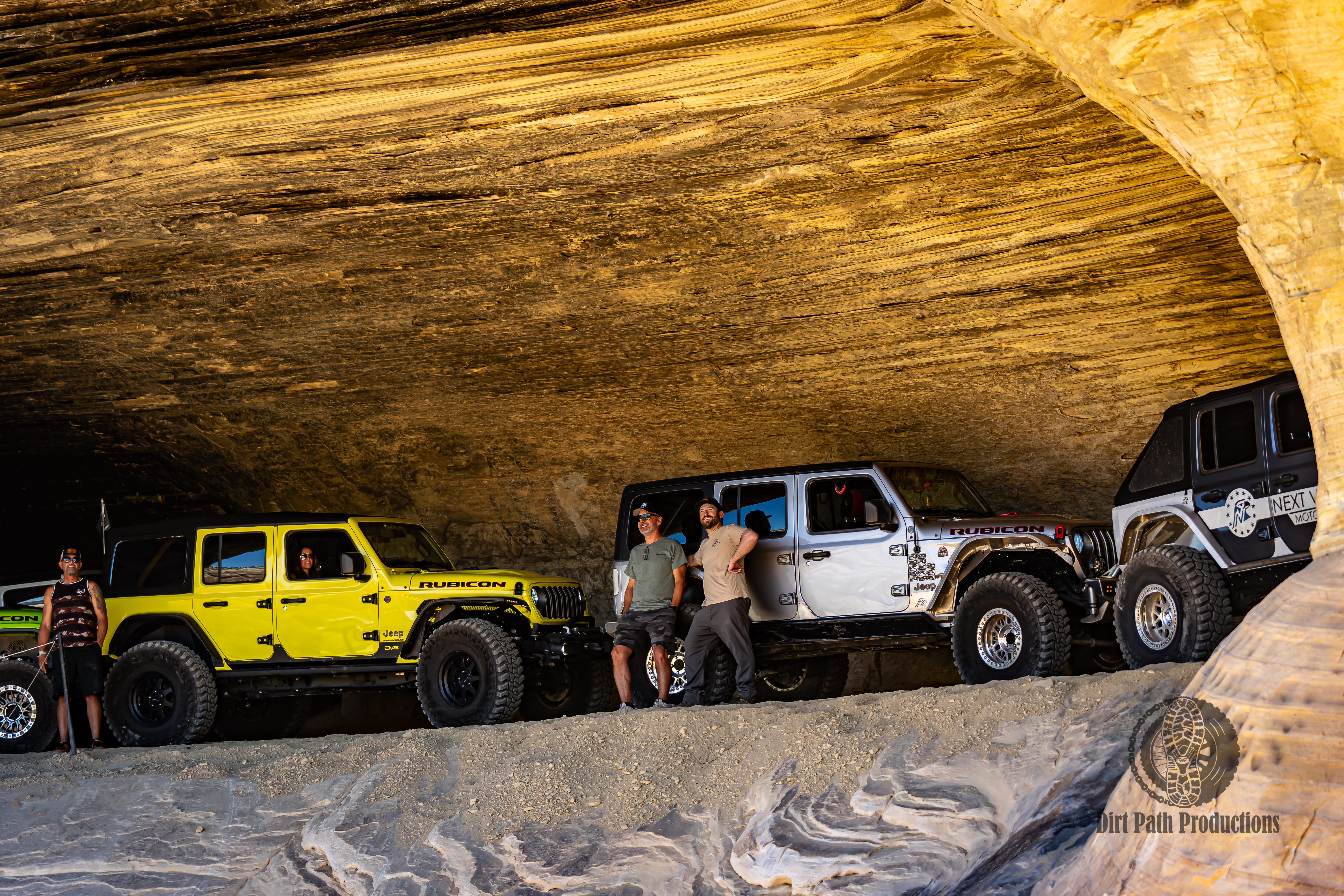 Jeeps parked under a massive sandstone arch