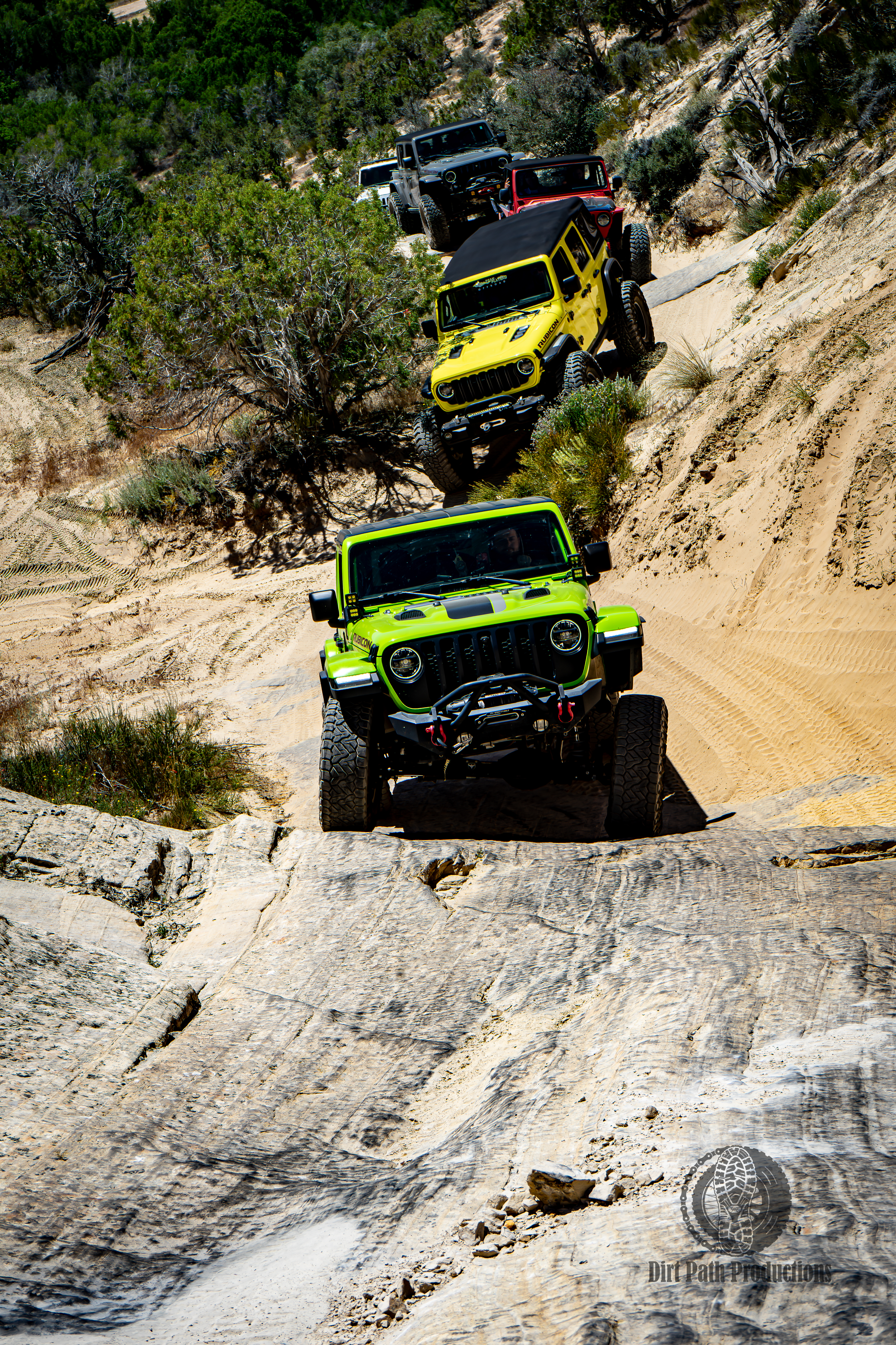 Jeeps lined up descending a slickrock trail